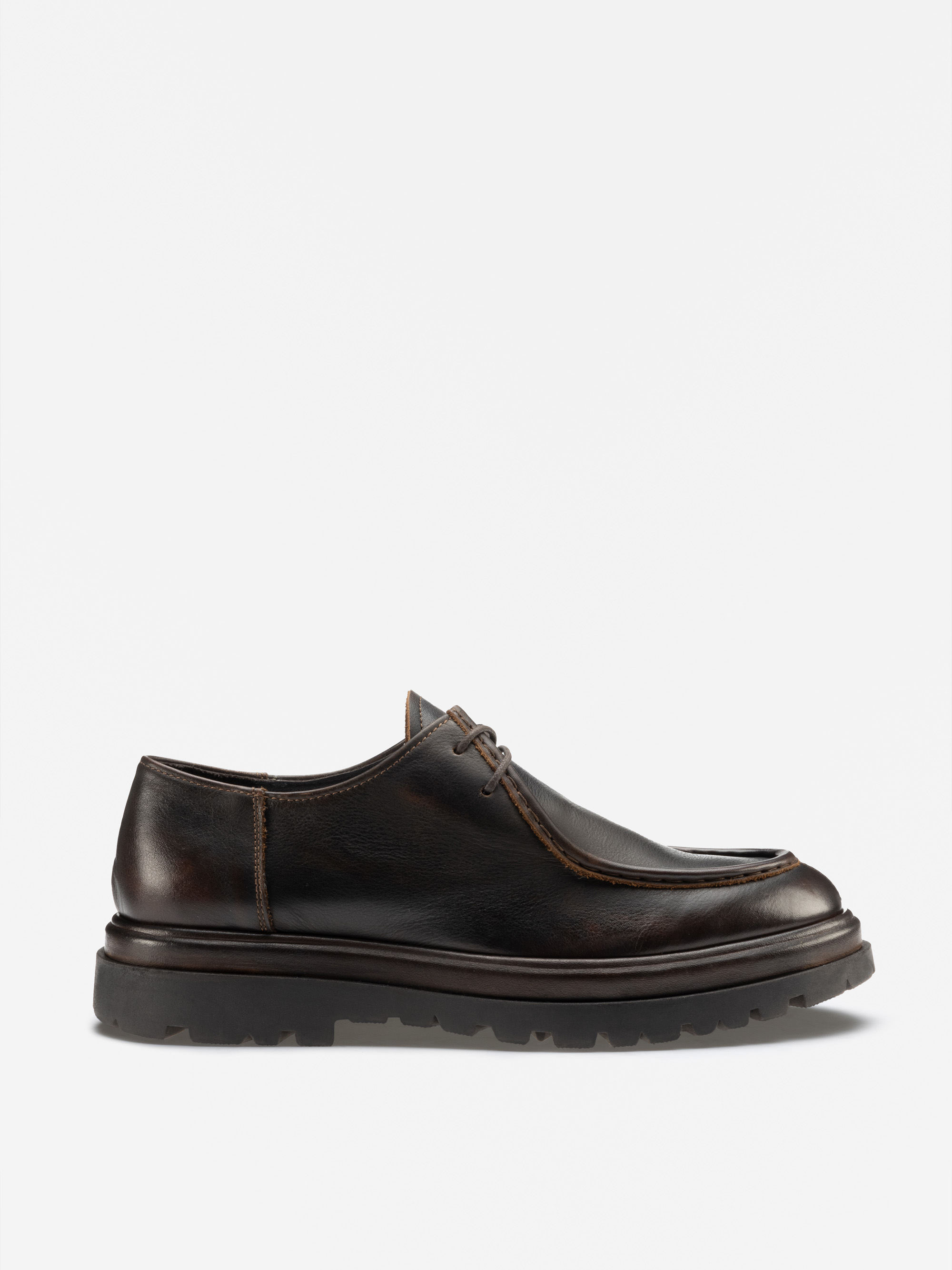 Ein dunkelbrauner Lederschnürschuh mit einer klobigen schwarzen Gummisohle und sichtbaren Nähten, im Profil auf einem schlichten weißen Hintergrund dargestellt.