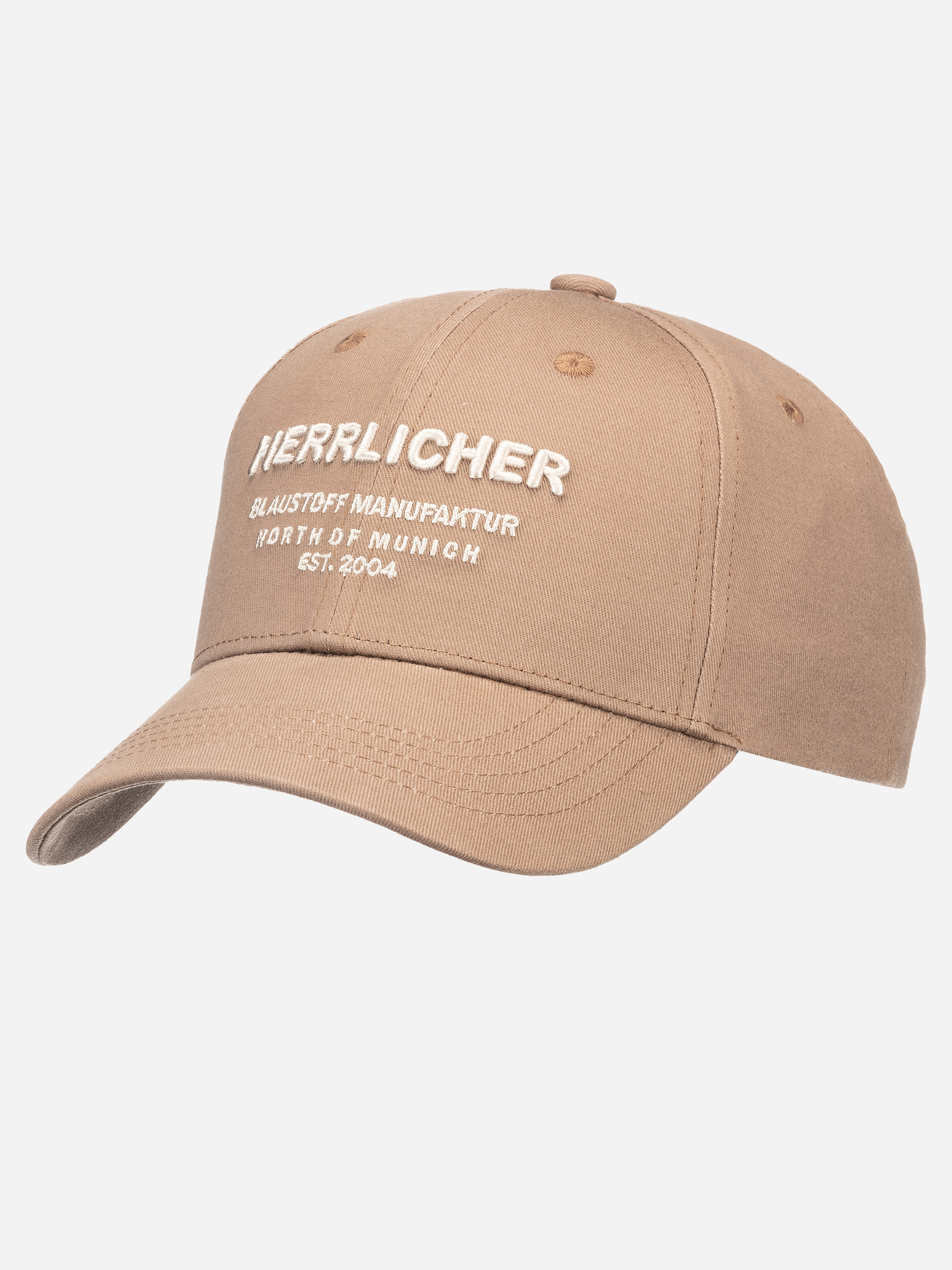 Eine hellbraune Baseballkappe mit weißem gesticktem Text auf der Vorderseite: Herrlicher Blaustoff Manufaktur North of Munich Est. 2004, dargestellt auf einem schlichten weißen Hintergrund.