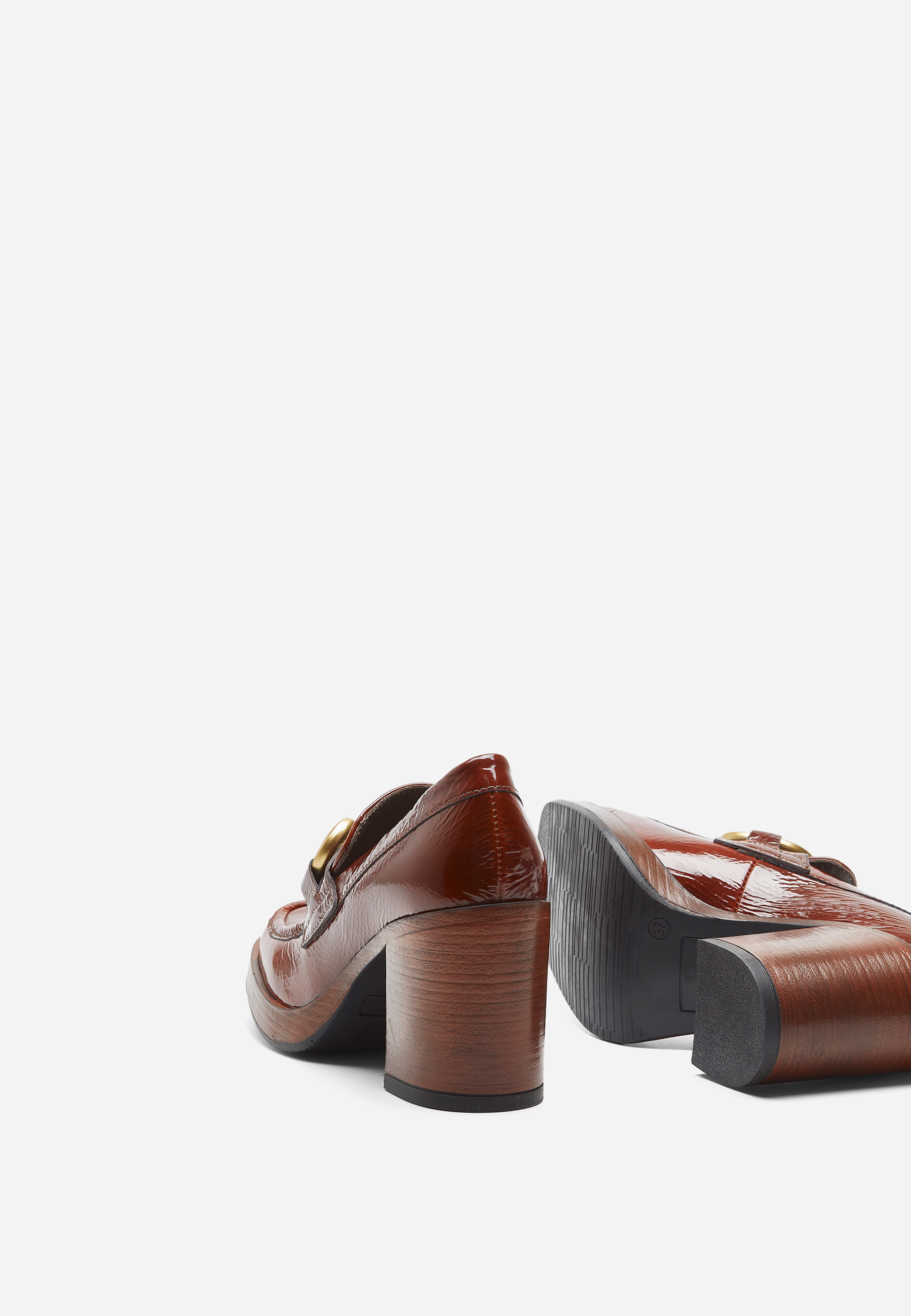Ein Paar brauner, glänzender Slipper mit Absatz, strukturiertem Leder und goldenen Verzierungen, von hinten und von der Seite auf weißem Hintergrund dargestellt.