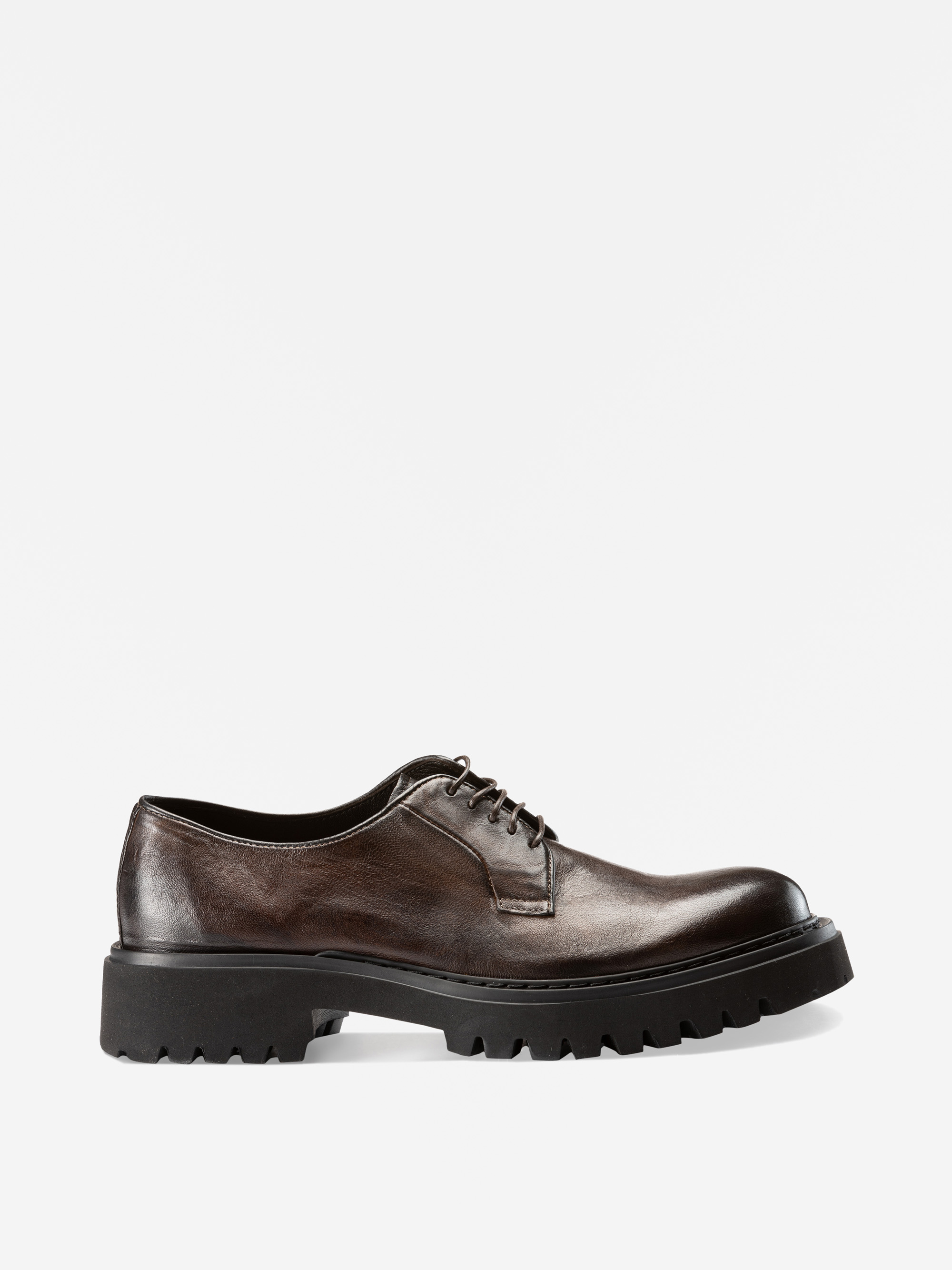 Ein einzelner dunkelbrauner Leder-Oxford-Schuh mit schwarzen Schnürsenkeln und einer dicken, robusten schwarzen Gummisohle, dargestellt im Profil vor einem schlichten weißen Hintergrund.