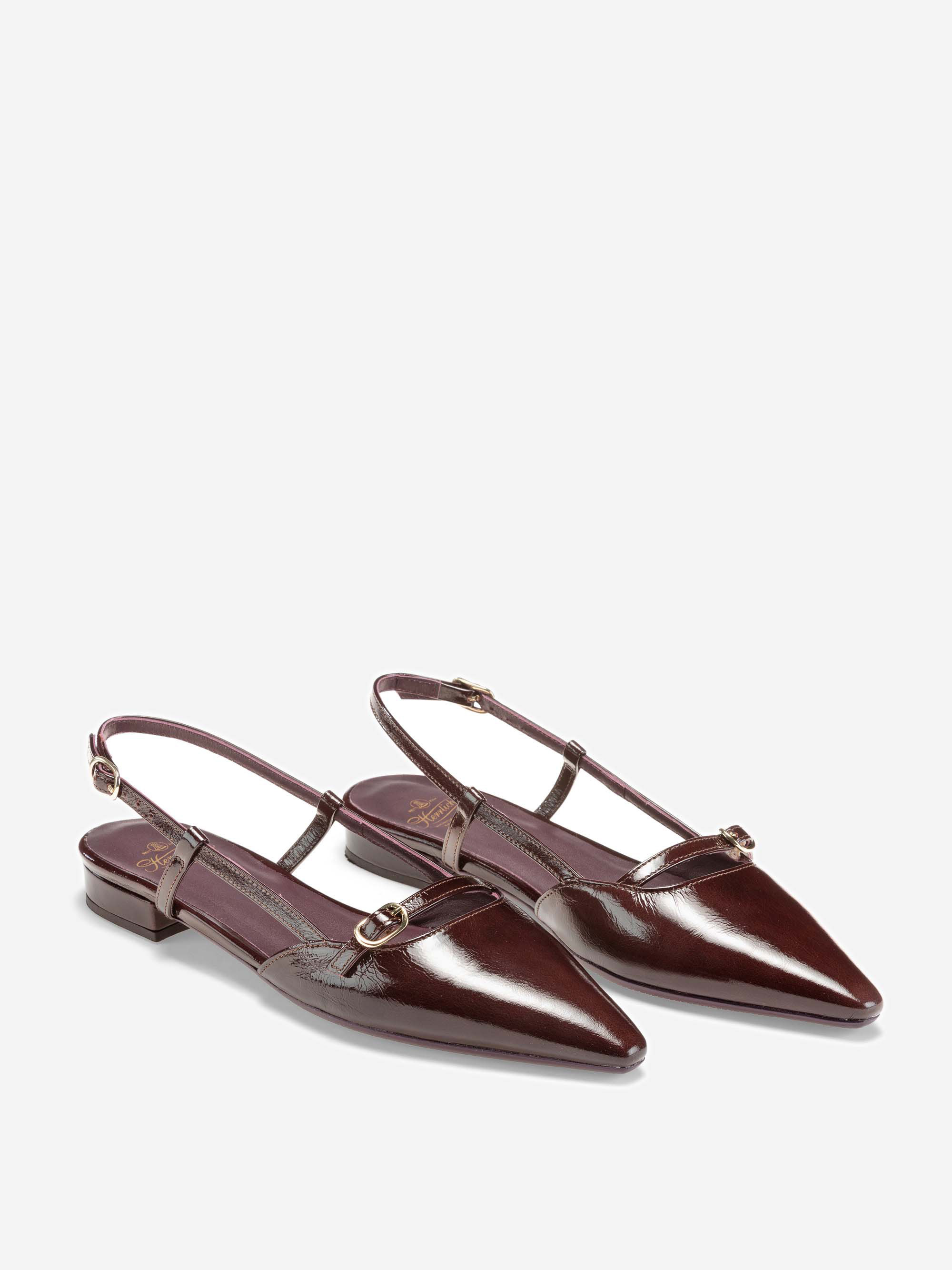 Ein Paar glänzender, dunkelburgunderfarbener, spitz zulaufender Slingback-Flats mit niedrigem Absatz, schmalen Riemen und kleinen goldenen Schnallen auf weißem Hintergrund.