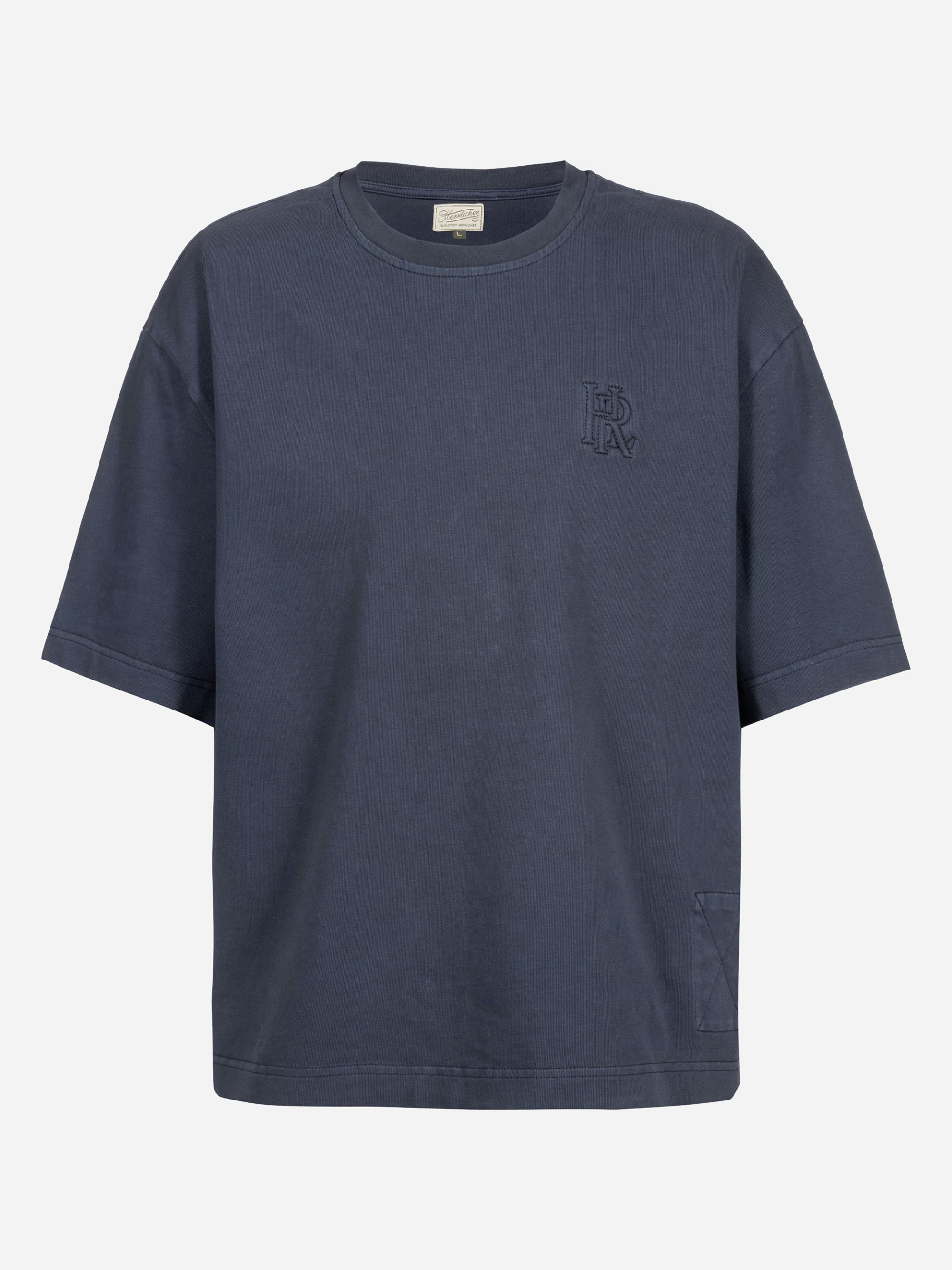 Ein locker sitzendes, kurzärmeliges, marineblaues T-Shirt mit einem kleinen gestickten LDAC-Logo auf der linken Brust und einem aufgenähten quadratischen Aufnäher in der Nähe des unteren Saums auf der rechten Seite.