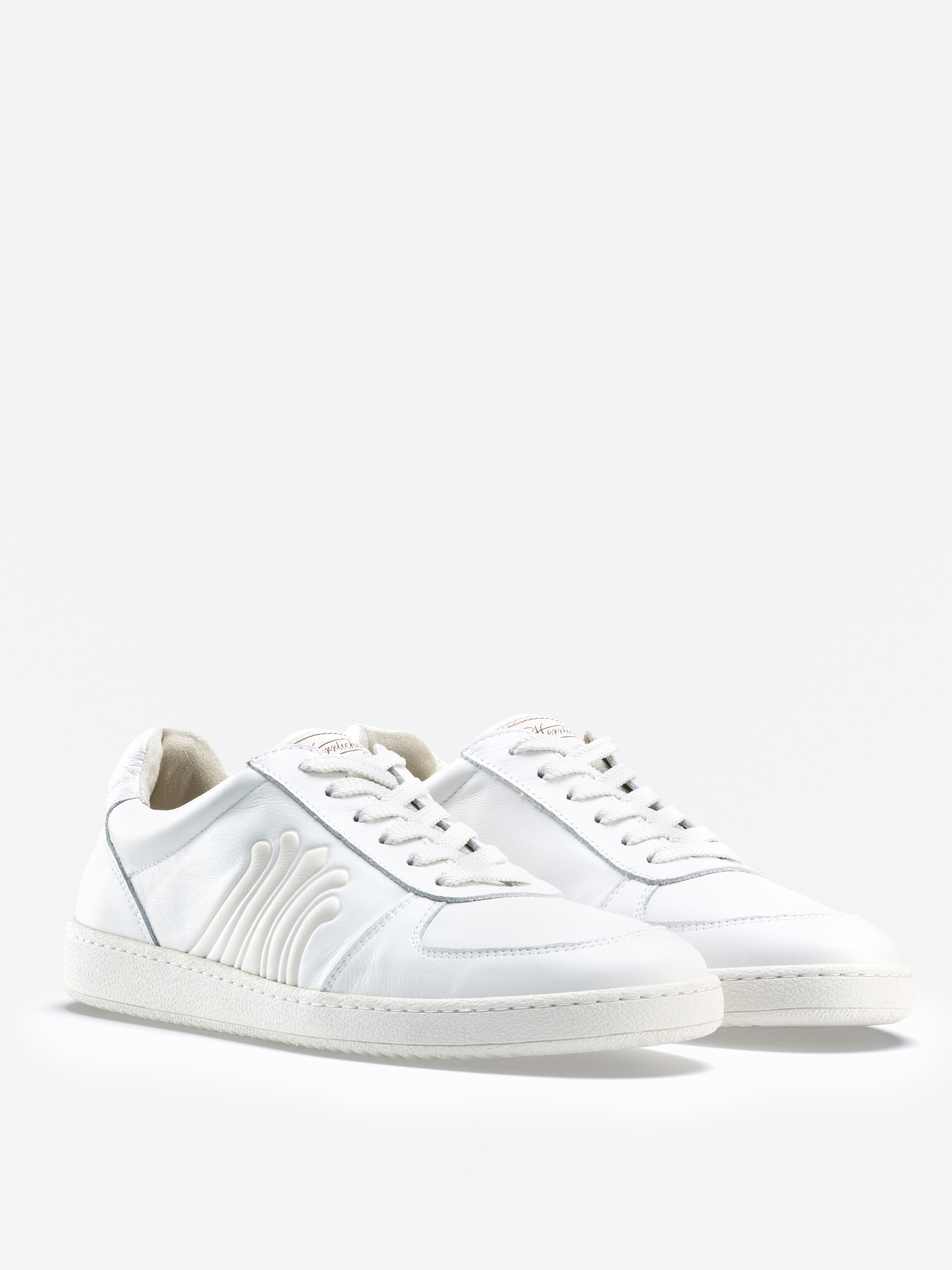 Ein Paar weiße Low-Top-Sneaker mit weißen Schnürsenkeln und einer strukturierten weißen Sohle. Die Seite weist ein subtiles wellenförmiges Design auf. Die Schuhe sind schräg auf einem schlichten weißen Hintergrund positioniert.