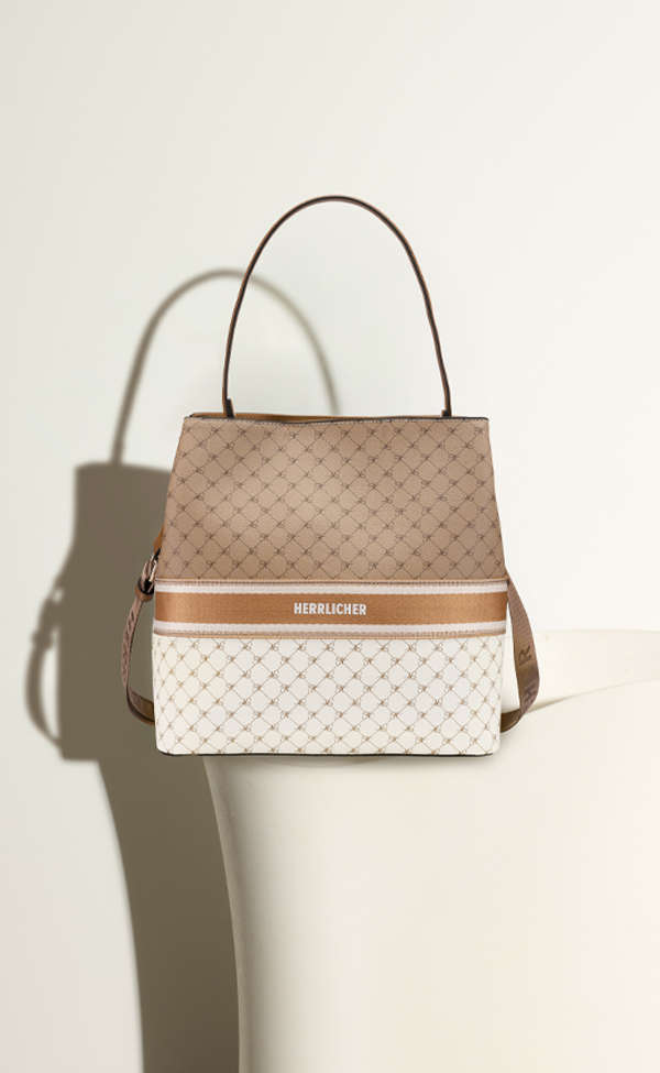 Eine stilvolle Handtasche in Beige und Weiß mit geometrischem Muster, Tragegriff und dem Markennamen „Herrlicher“ auf der Vorderseite, vor einem hellen Hintergrund mit sanften Schatten.