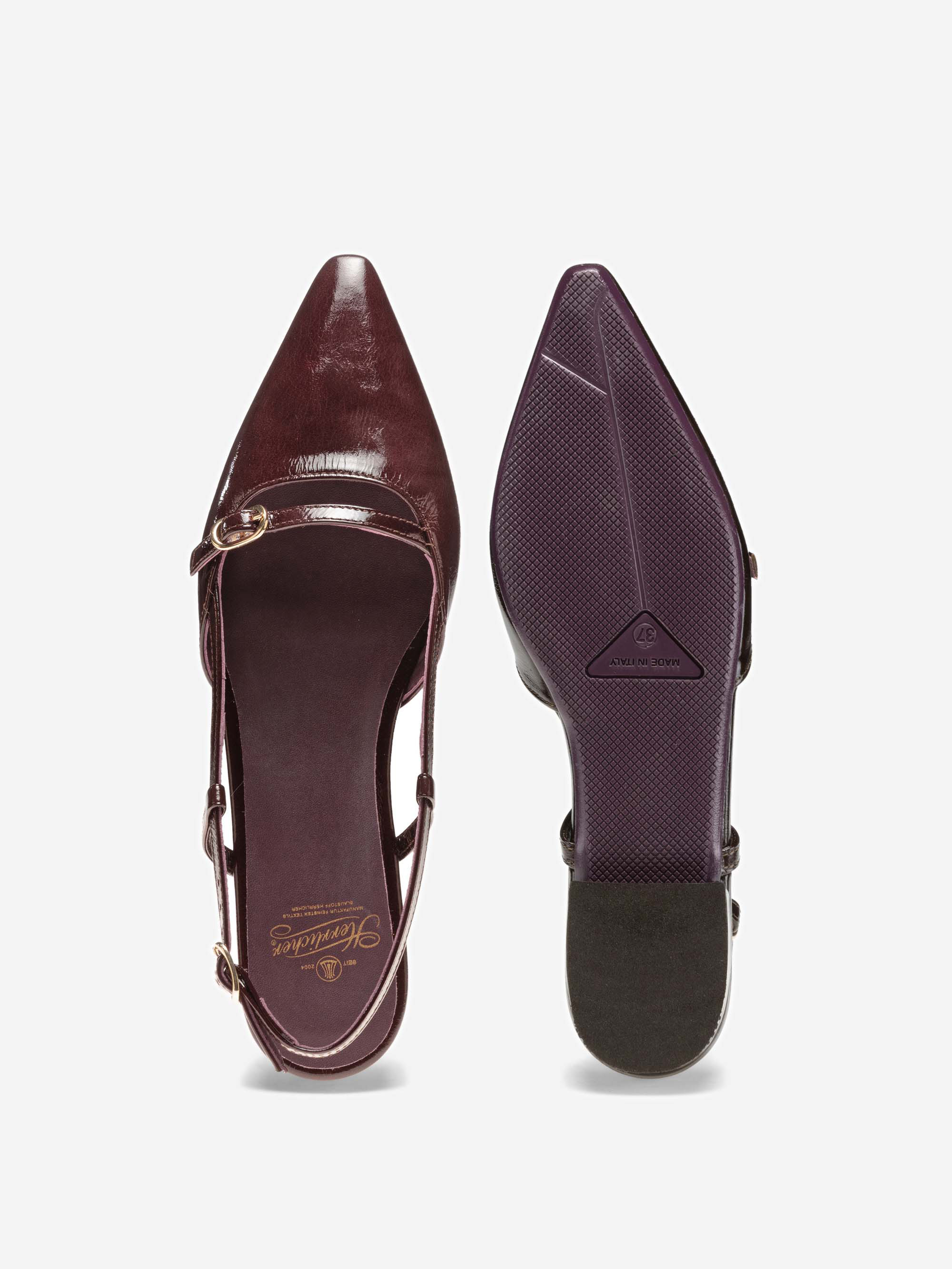 Ein Paar spitz zulaufende Slingback-Schuhe aus bordeauxfarbenem Lackleder mit zwei Riemen und goldenen Schnallen; ein Schuh ist von oben nach unten dargestellt, der andere zeigt die strukturierte Sohle.