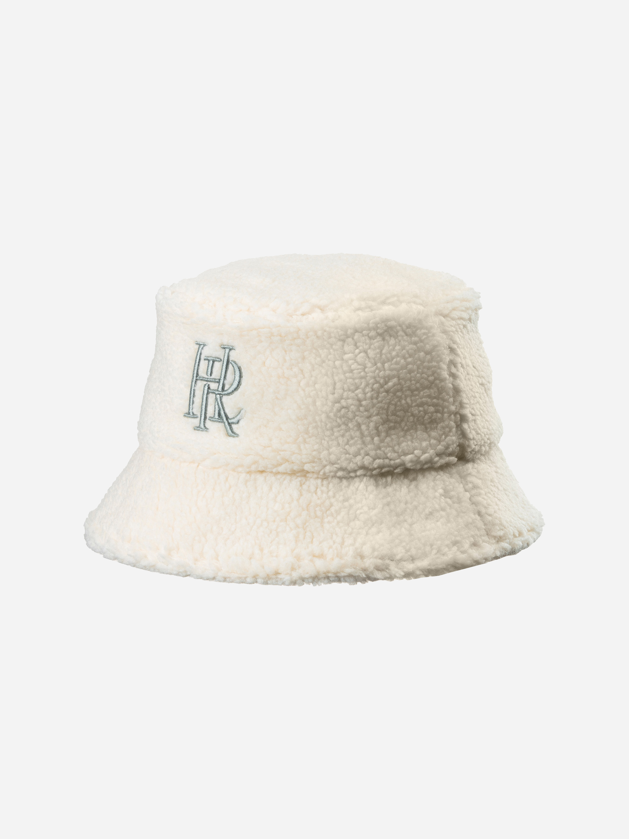 Eine cremefarbene, flauschige Sherpa-Mütze mit einem gestickten Monogramm HR in Hellblau auf der Vorderseite, das auf einem schlichten weißen Hintergrund abgebildet ist.