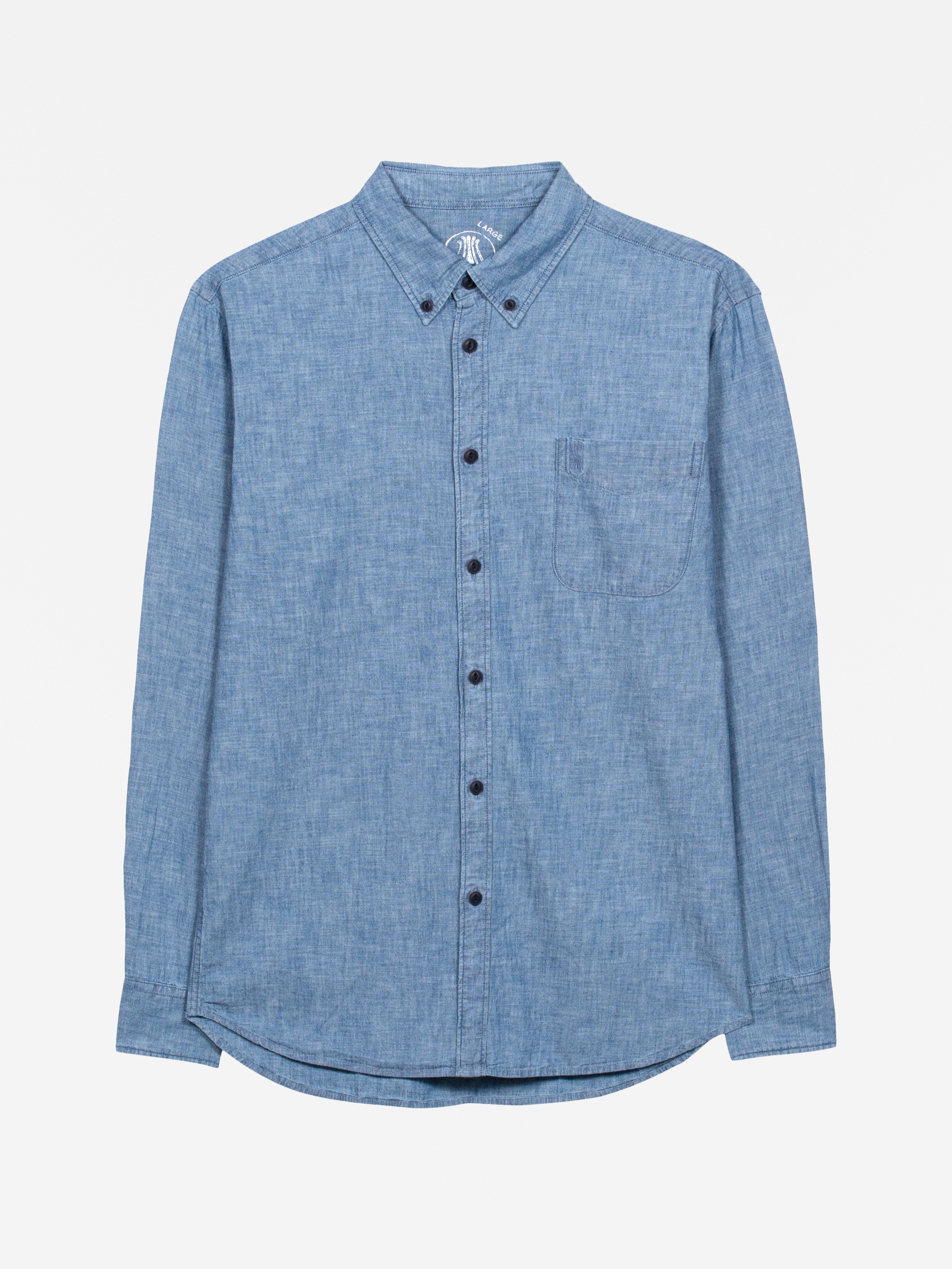 Ein langärmeliges, geknöpftes, hellblaues Chambray-Hemd mit einer einzigen Brusttasche, flach auf weißem Hintergrund.