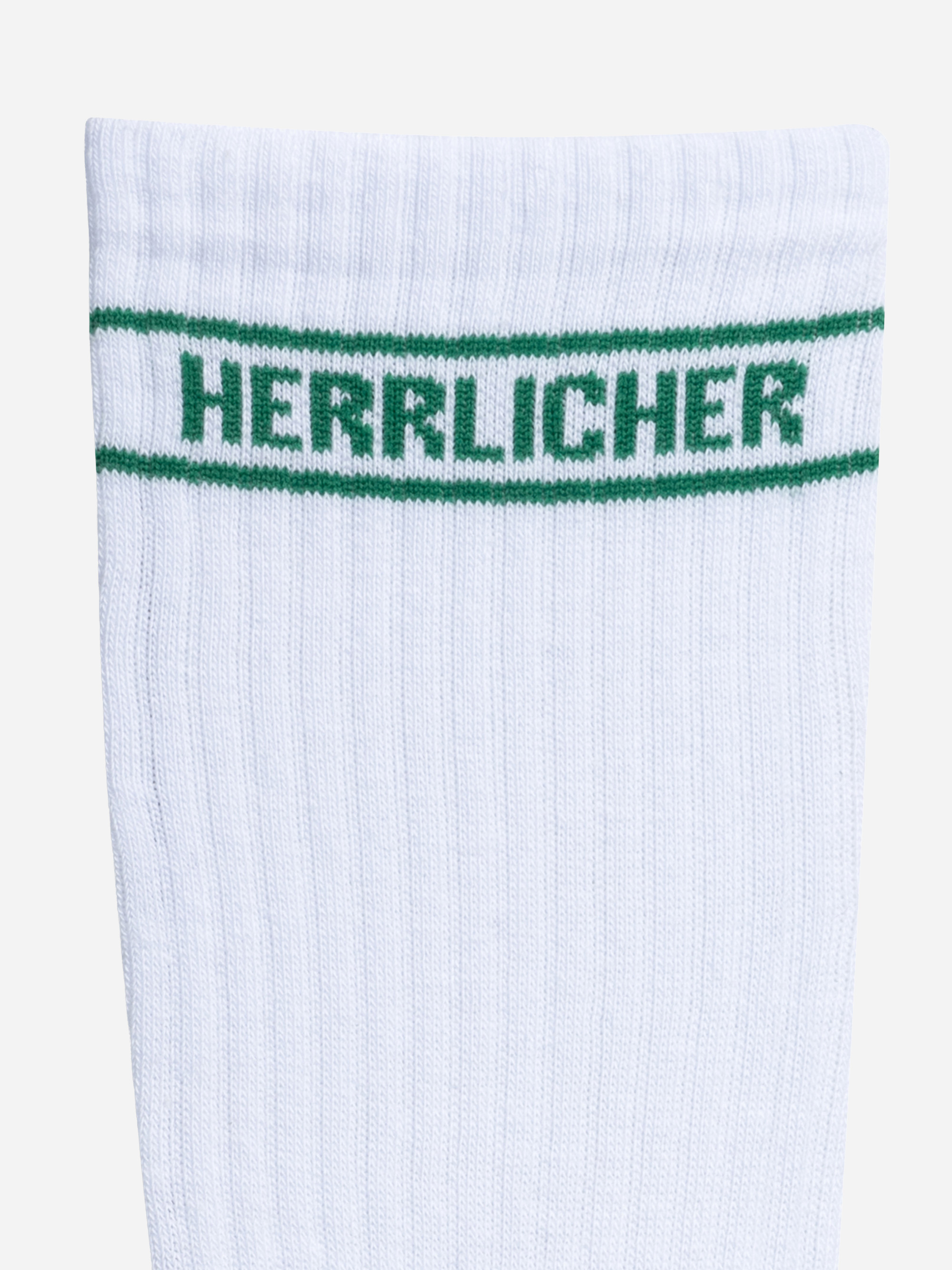 Nahaufnahme des oberen Teils einer weißen gerippten Socke mit zwei grünen Streifen und dem Wort HERRLICHER in grüner Farbe zwischen den Streifen.
