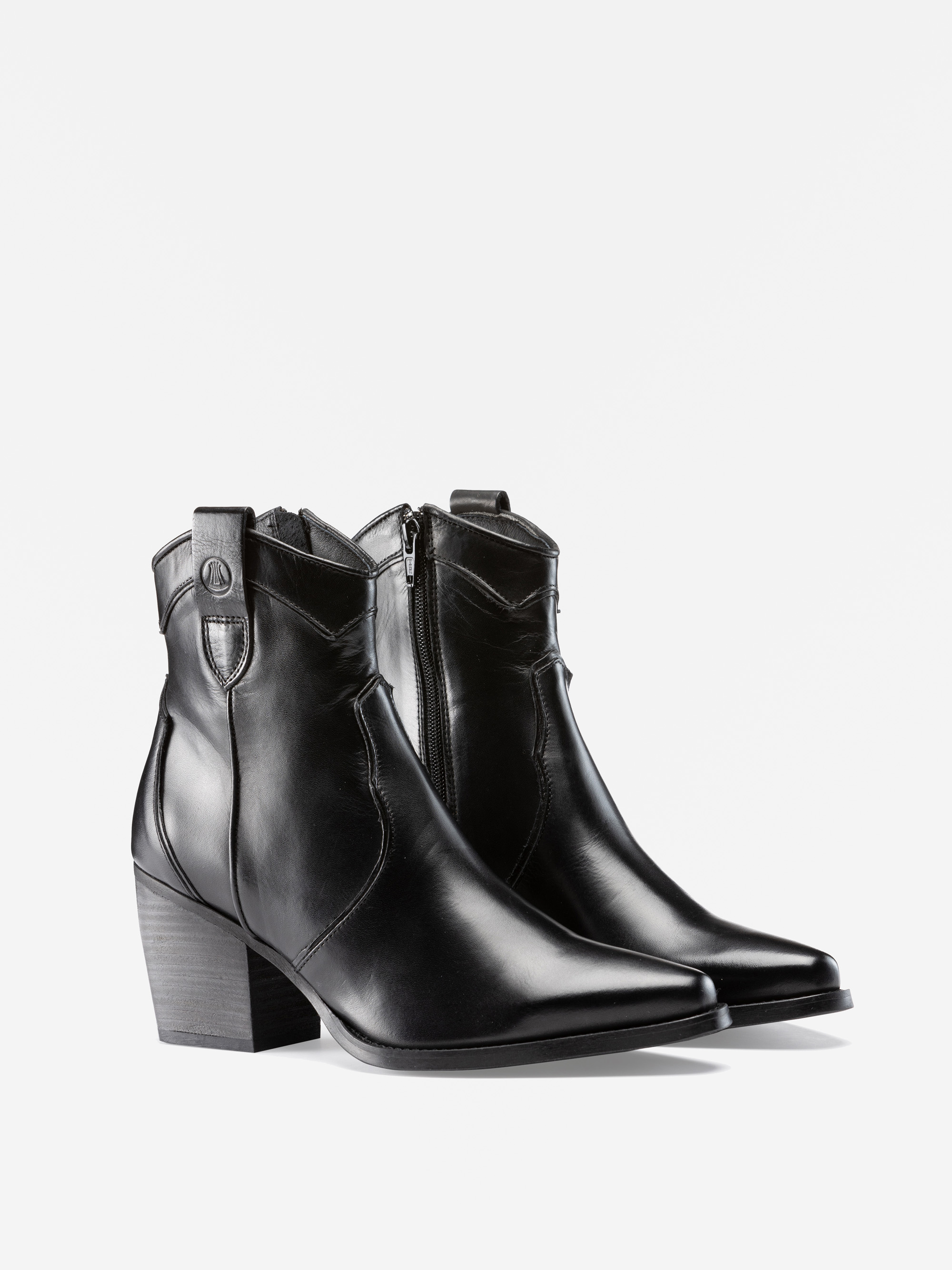 Ein Paar schwarze Lederstiefel mit seitlichen Reißverschlüssen, spitzen Zehen und klobigen Absätzen, die vor einem schlichten weißen Hintergrund stehen.