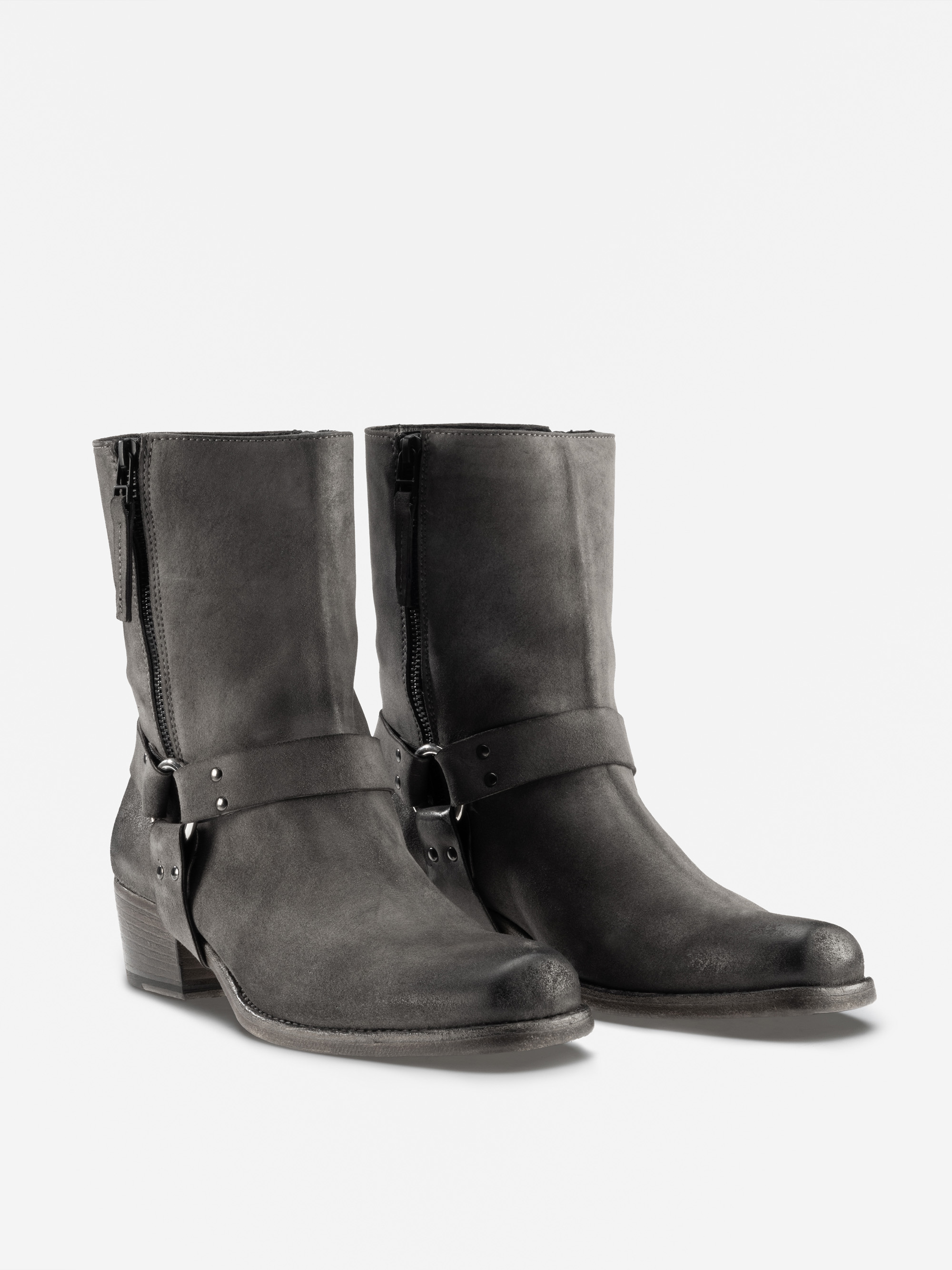 Ein Paar schwarze, halbhohe Lederstiefel mit seitlichen Reißverschlüssen, einem dicken, niedrigen Absatz und dekorativen Riemen mit Metallringen und Nieten um die Knöchel, dargestellt auf einem schlichten weißen Hintergrund.