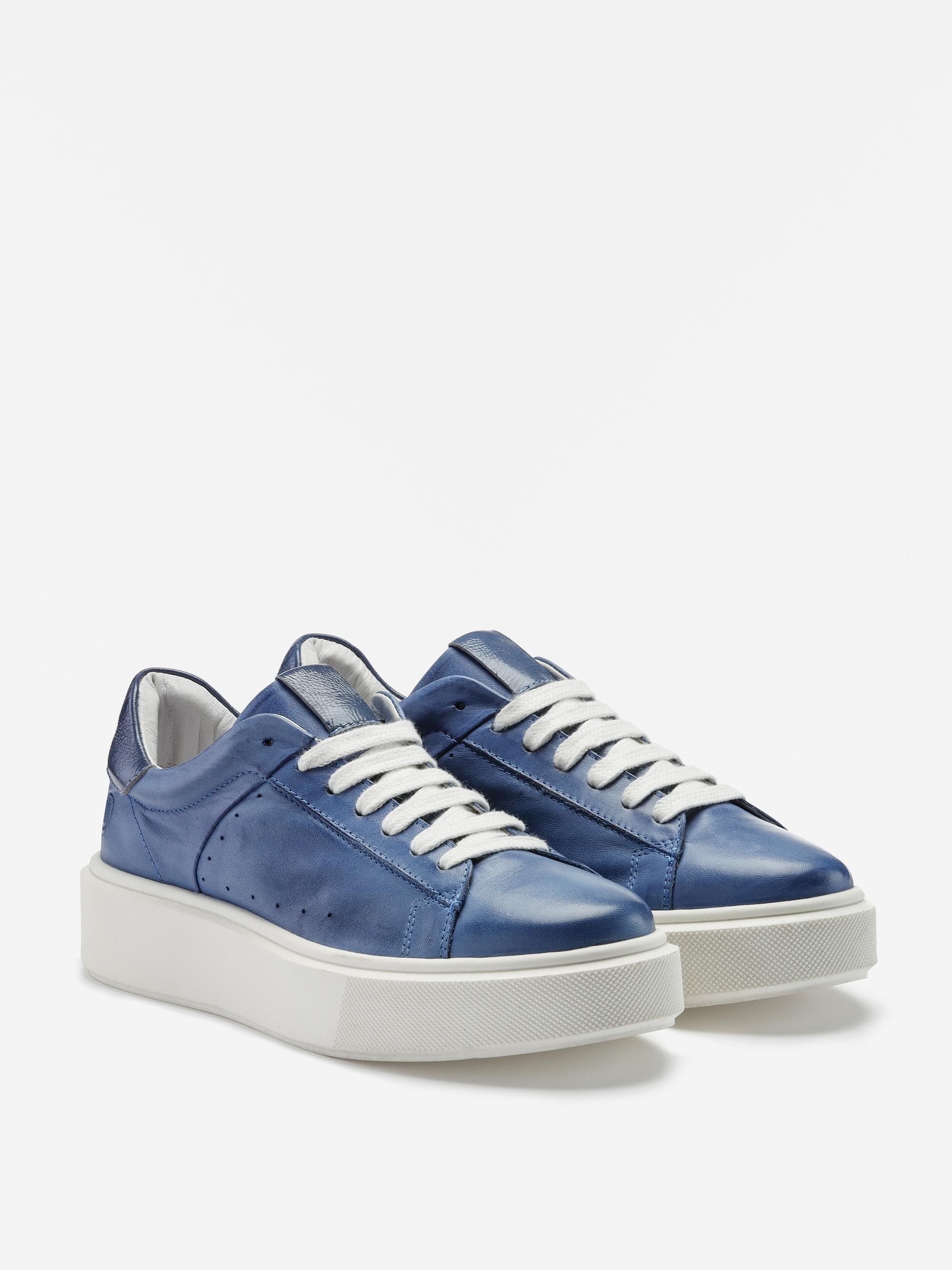 Ein Paar blaue Lederturnschuhe mit weißen Schnürsenkeln und dicken weißen Gummisohlen, die vor einem schlichten weißen Hintergrund stehen.