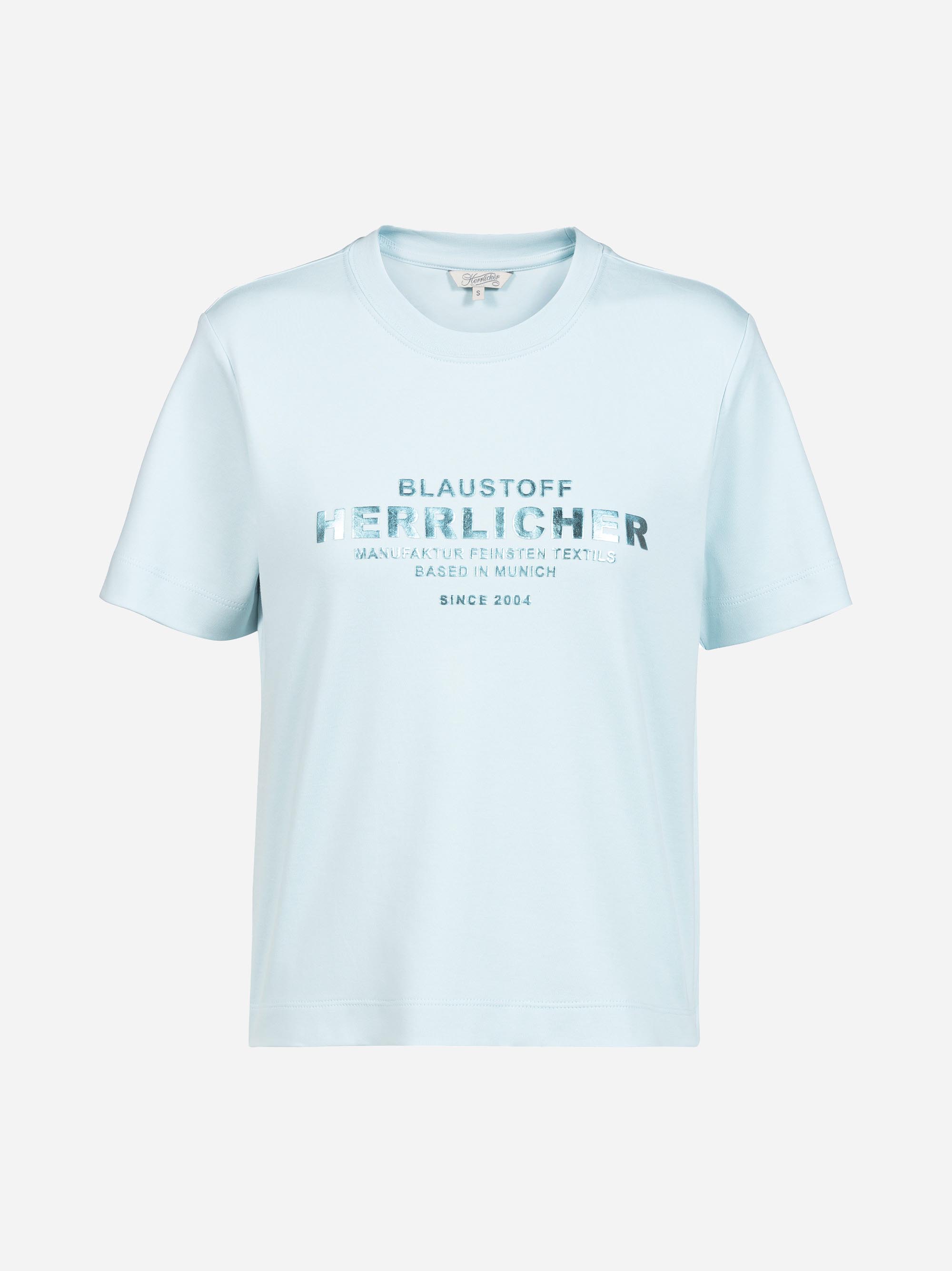 Hellblaues Kurzarm-T-Shirt mit der Aufschrift BLAUSTOFF HERZLICHER MANUFAKTUR FEINSTER TEXTILIEN BASED IN MUNICH SINCE 2004 in metallicblau auf der Vorderseite.