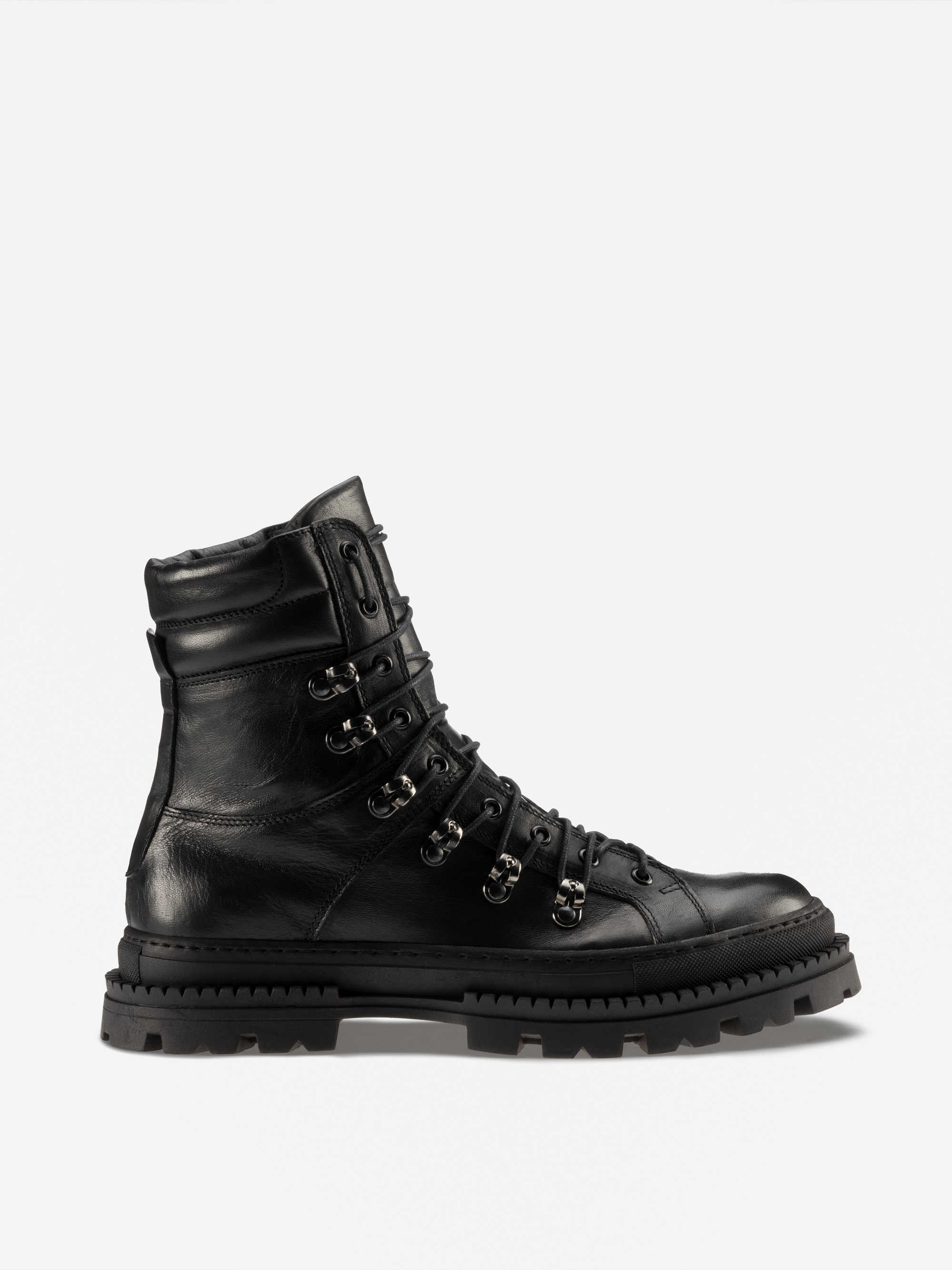 Ein schwarzer Schnürstiefel aus Leder mit Metallösen, robuster Sohle und knöchelhohem Design, von der Seite auf weißem Hintergrund gezeigt.