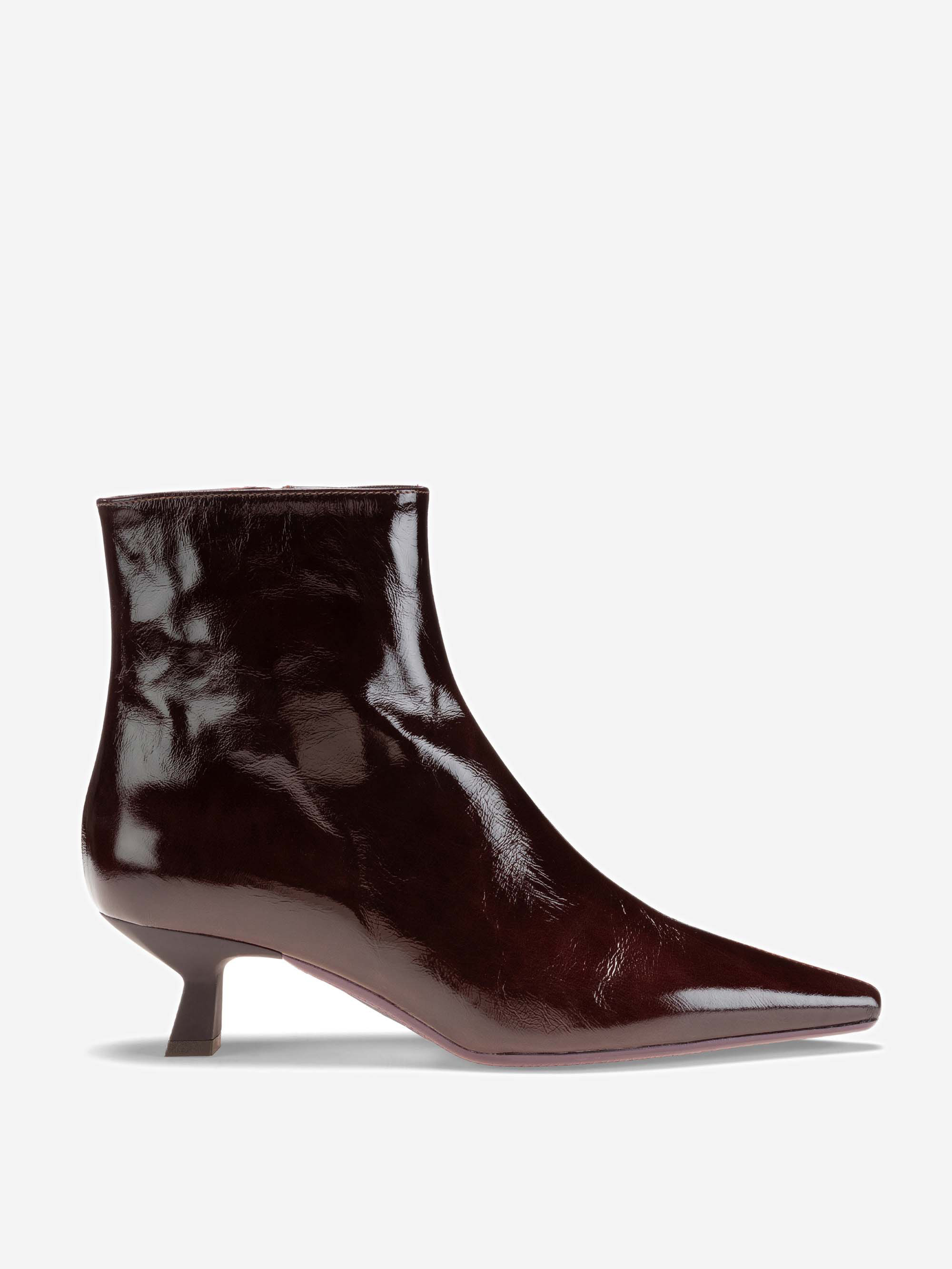 Eine glänzende, weinrote Stiefelette mit spitzer Spitze und kurzem, schrägem Absatz, dargestellt im Seitenprofil auf weißem Grund.