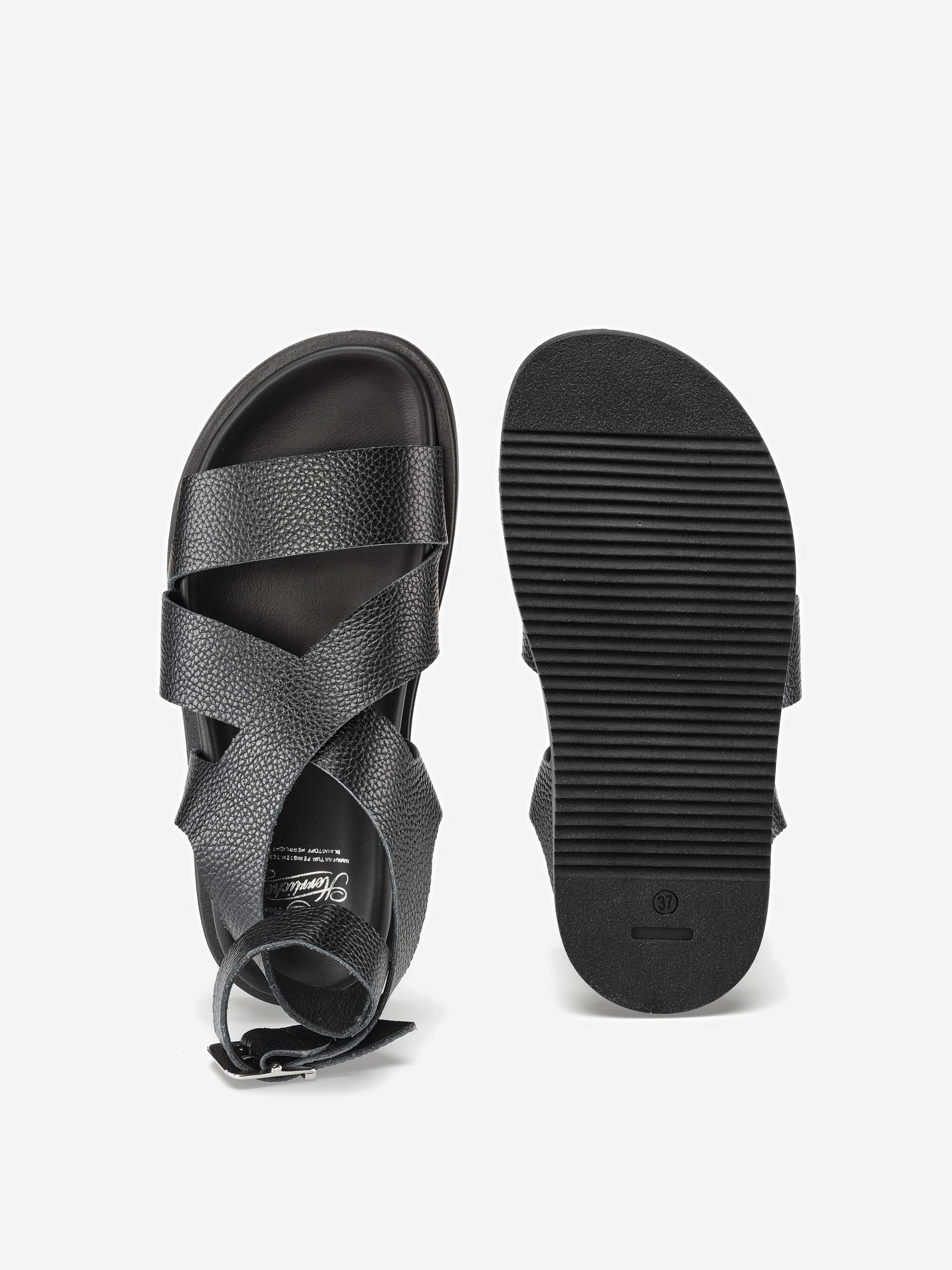 Ein Paar schwarze Sandalen mit strukturierten, gekreuzten Riemen und einer Knöchelschnalle. Eine Sandale ist von oben abgebildet, die andere zeigt die geriffelte Sohle auf weißem Hintergrund.