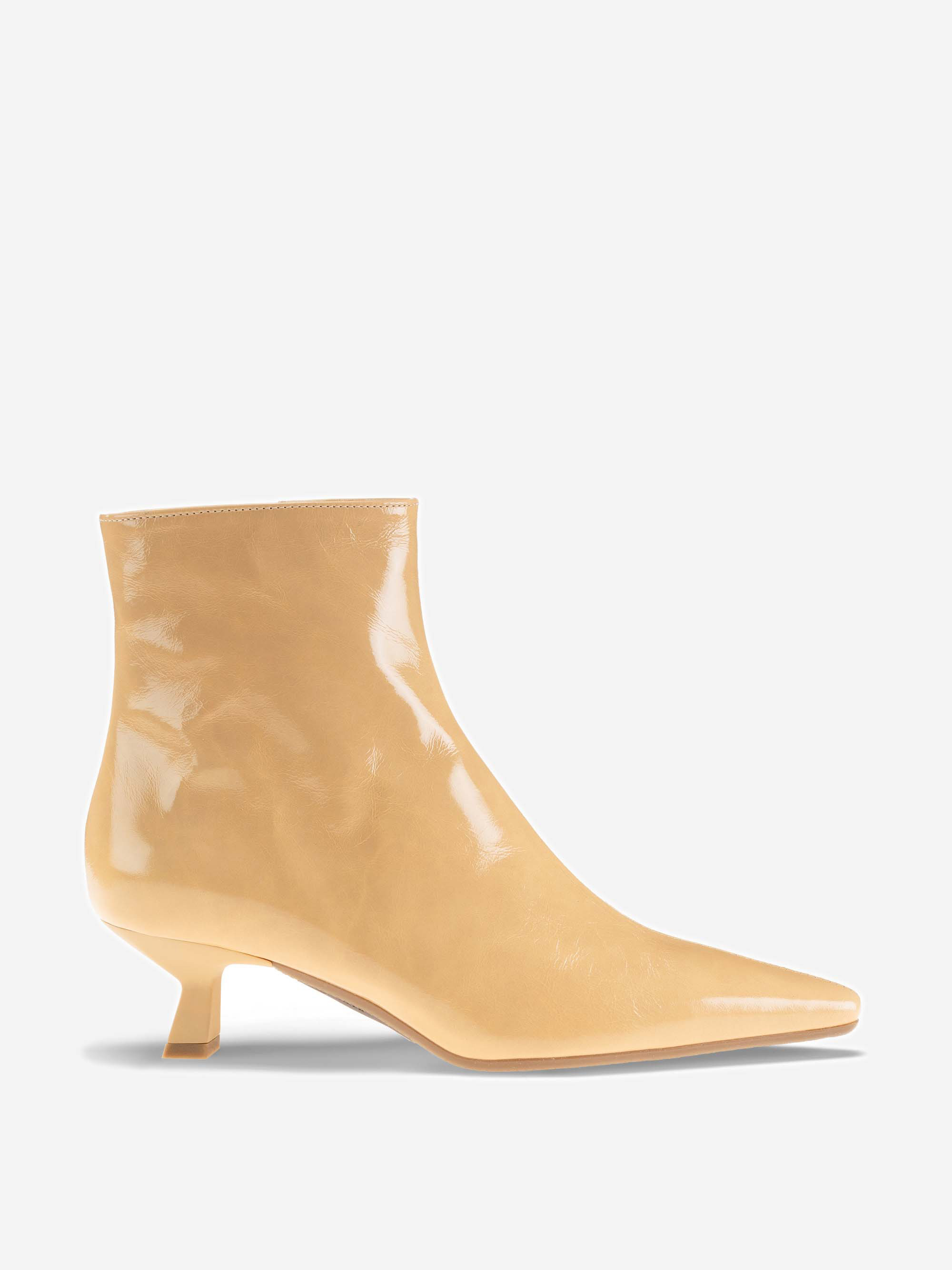 Eine beigefarbene, glänzende Stiefelette mit spitzer Spitze und kurzem, schrägem Kitten-Absatz, im Profil auf einem schlichten, hellen Hintergrund dargestellt.