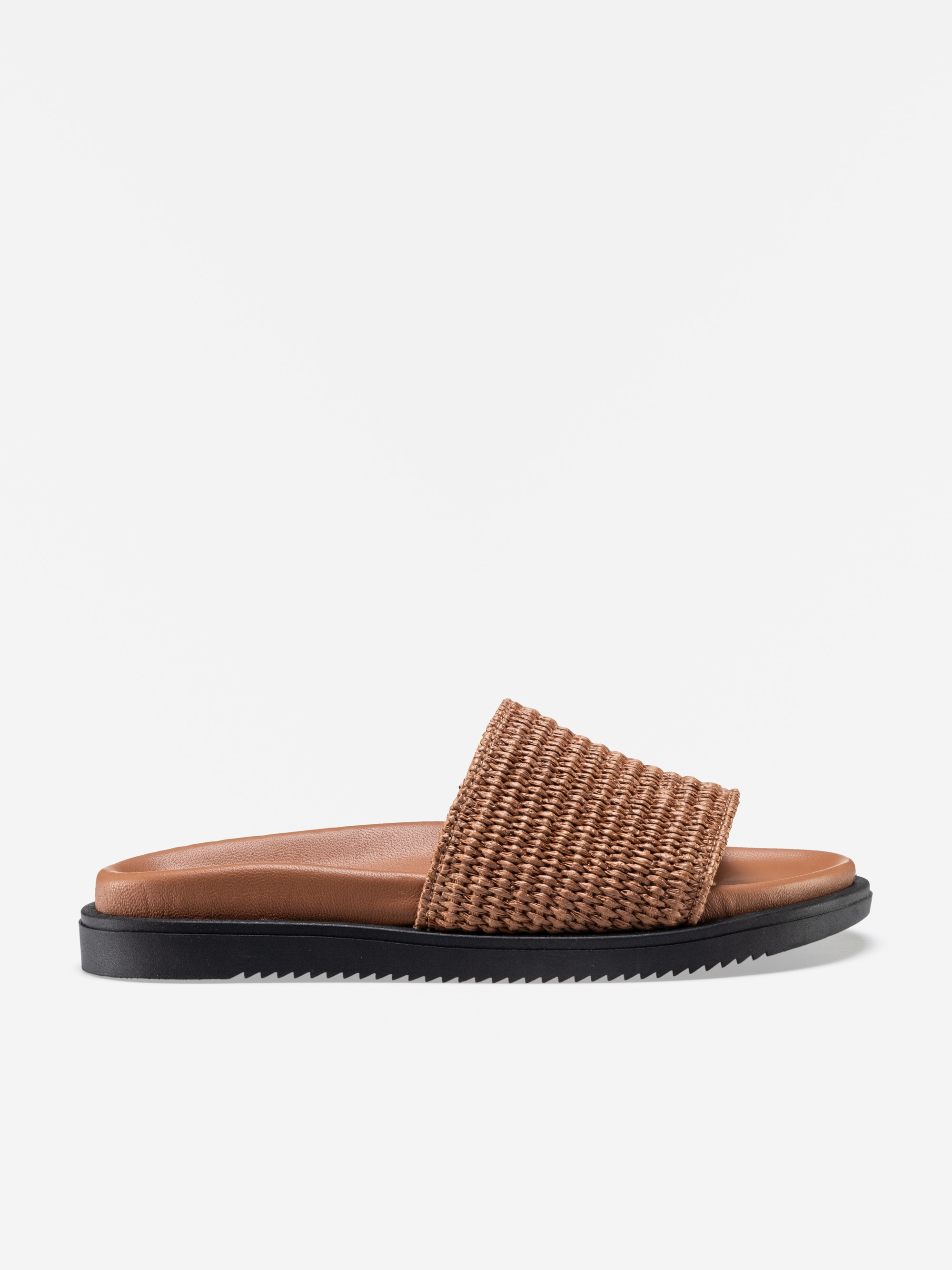 Eine braune, gewebte Slide-Sandale mit einem breiten, strukturierten Riemen, einer gepolsterten, hellbraunen Sohle und einer flachen, schwarzen Gummilaufsohle auf weißem Hintergrund.