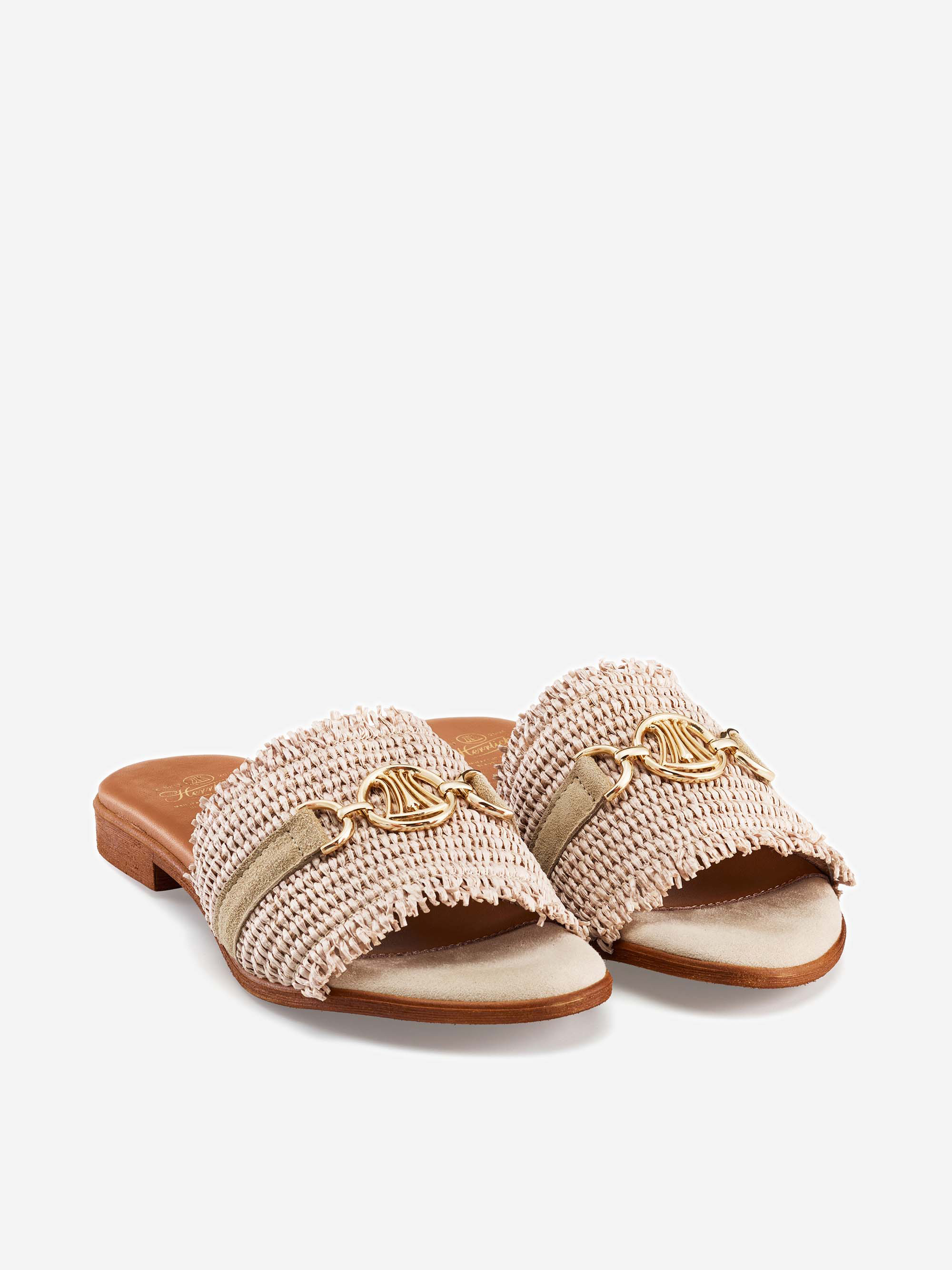 Beigefarbene, zehenoffene Gleitsandalen mit gewebten, strukturierten Riemen, goldenen Kettenakzenten und einem niedrigen, flachen Absatz auf weißem Hintergrund.