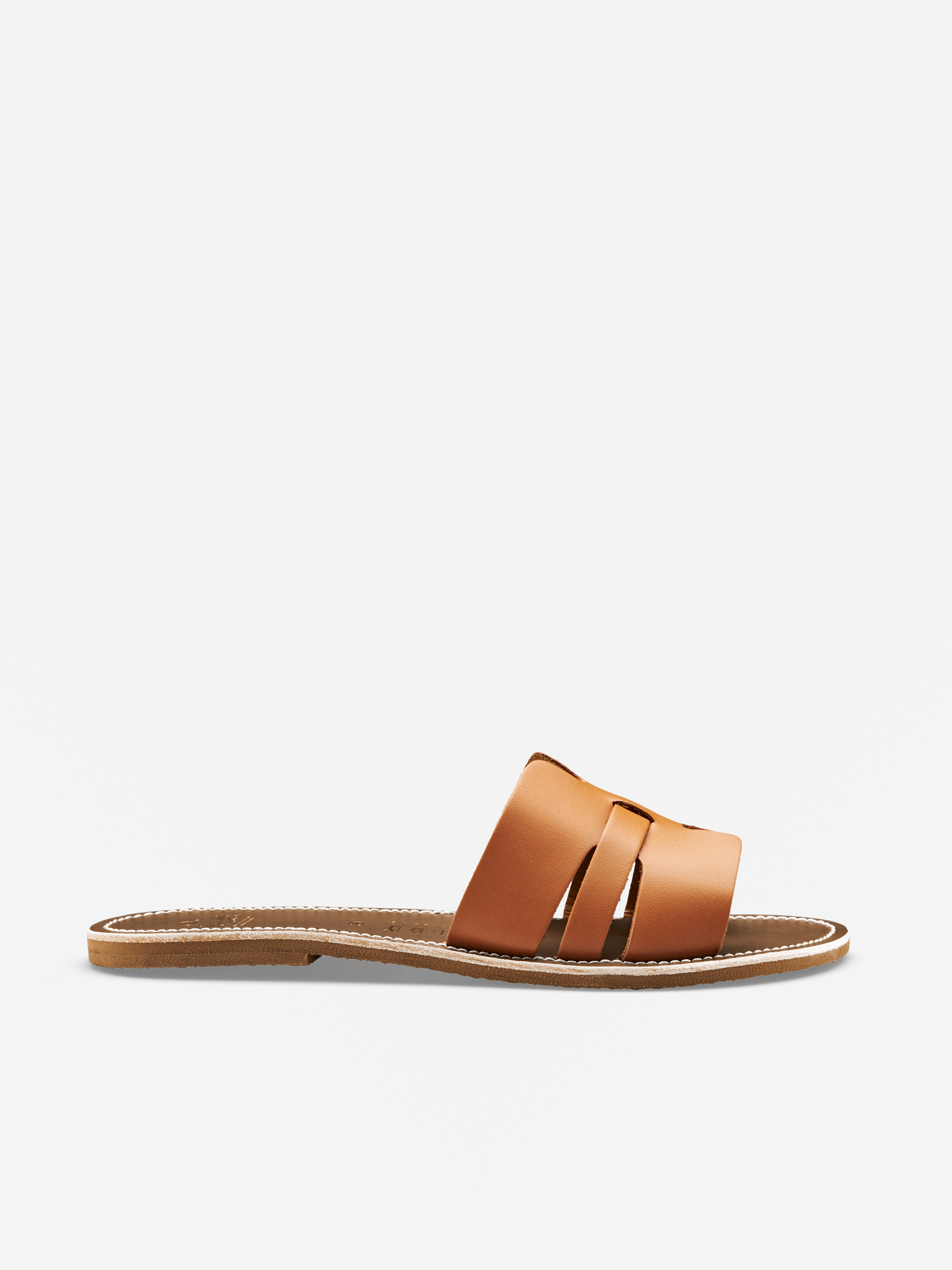 Eine braune, flache Slide-Sandale mit zwei breiten, überlappenden Lederriemen und einer dünnen, genähten Sohle, dargestellt im Seitenprofil auf einem schlichten weißen Hintergrund.