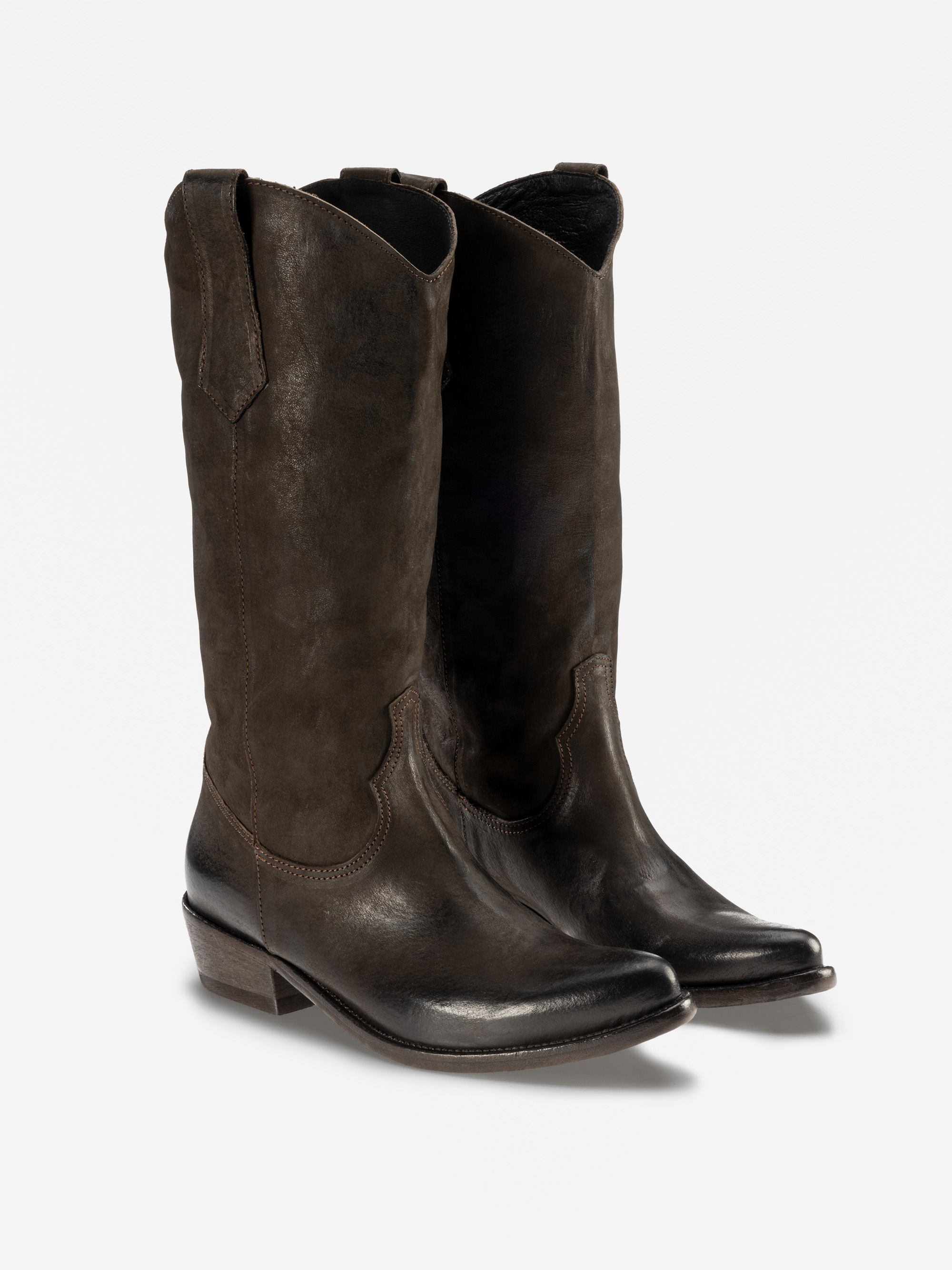 Ein Paar hohe, dunkelbraune Cowboystiefel aus Leder mit spitzen Zehen, Ziernähten und niedrigen, schrägen Absätzen, die aufrecht auf einem schlichten weißen Hintergrund stehen.