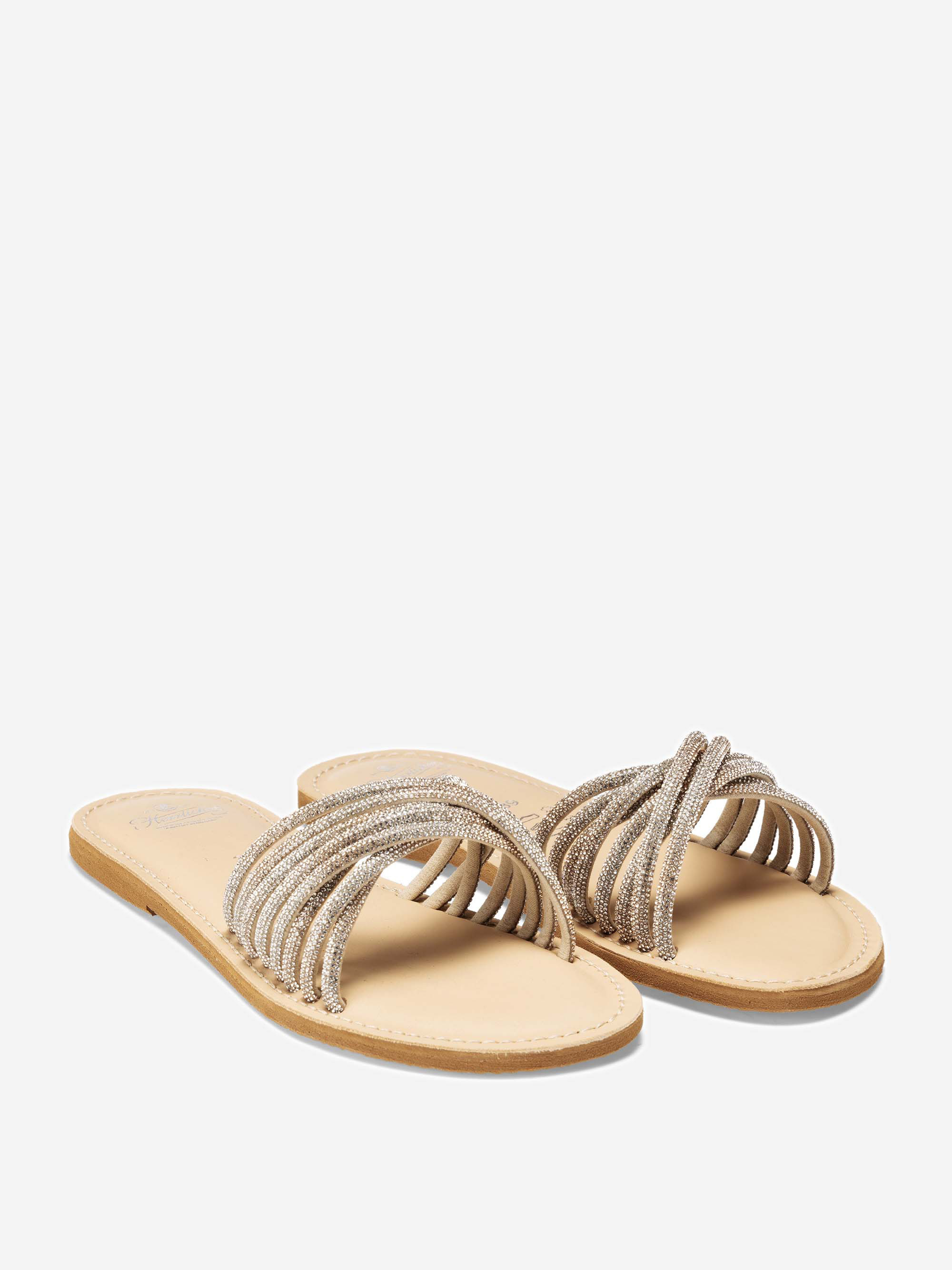 Ein Paar beigefarbene flache Sandalen mit hellbraunen Sohlen und breiten, mehrriemigen Metallbändern, die sich über den oberen Teil jedes Fußes erstrecken.