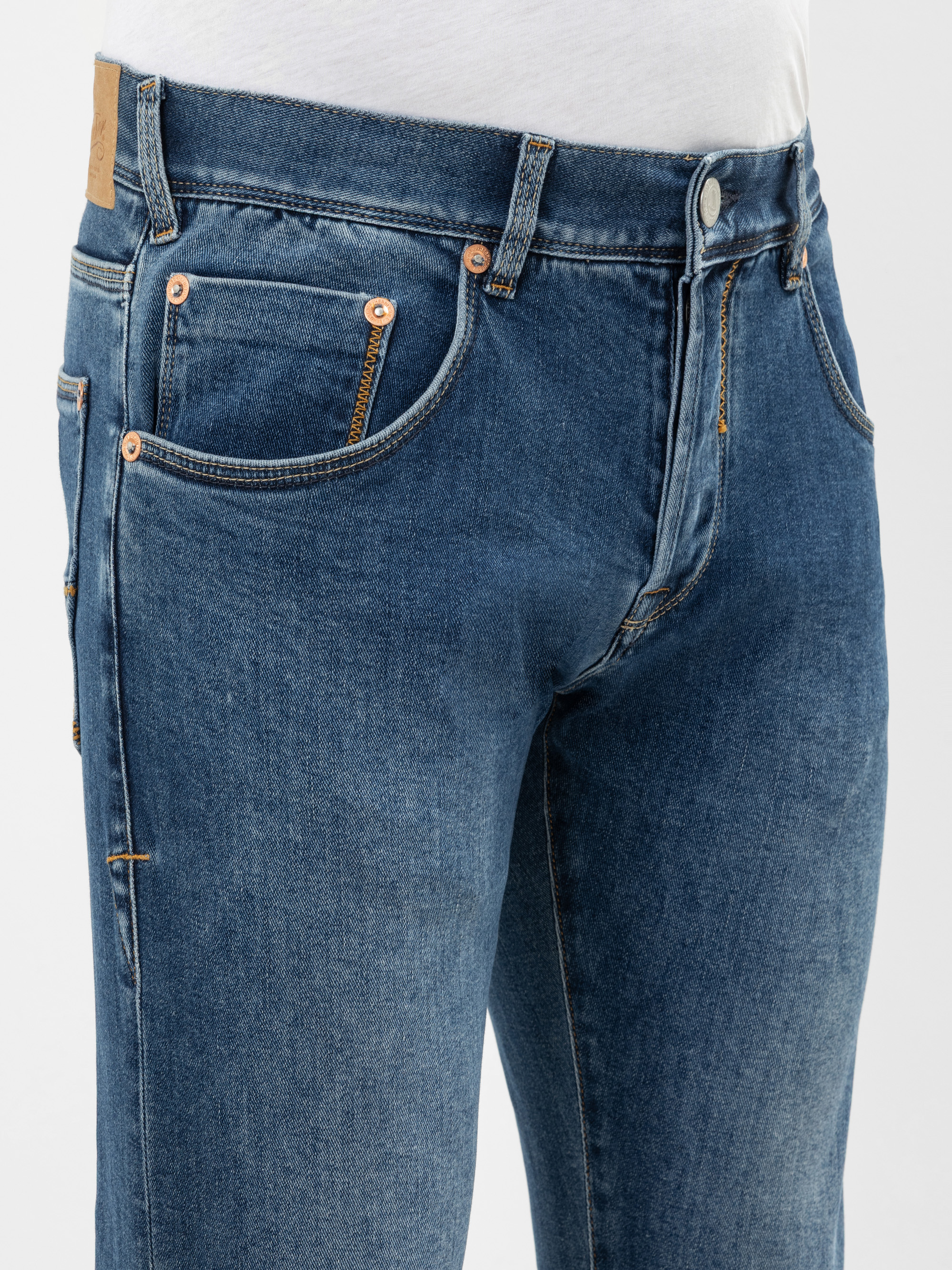 Nahaufnahme einer Person, die eine blaue Jeans und ein weißes Hemd trägt, wobei der Schwerpunkt auf der vorderen Tasche und dem oberen Beinbereich der Jeans liegt.