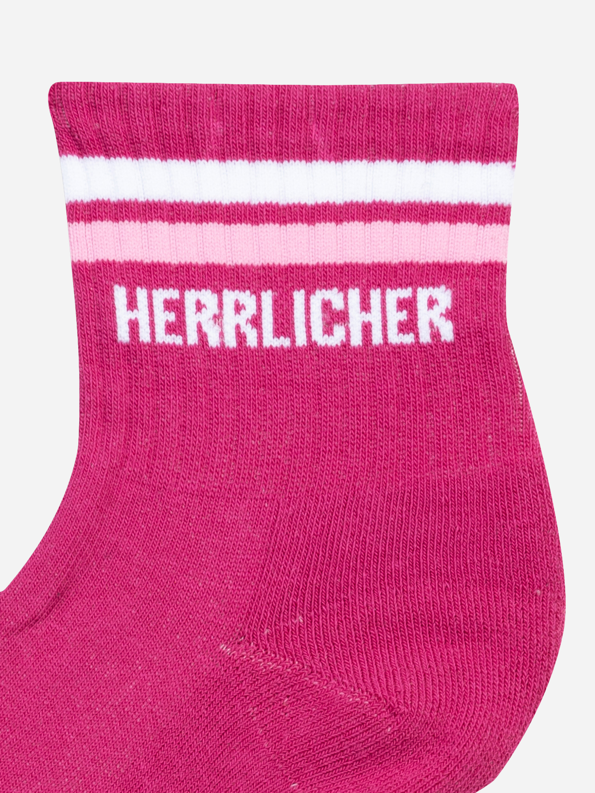 Nahaufnahme einer leuchtend rosafarbenen Socke mit zwei horizontalen weißen und rosafarbenen Streifen am oberen Rand und dem Wort HERRLICHER in weißer Schrift unterhalb der Streifen.